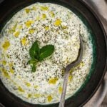 Turkish cacik in a bowl garnished with mint and olive oil.