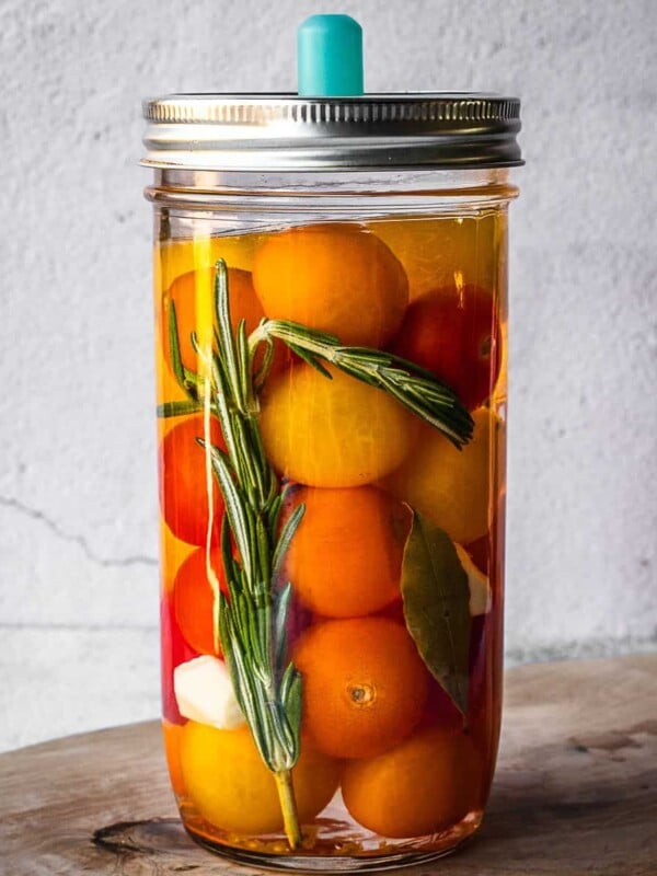 Mason jar with rosemary, garlic, bay and cherry tomatoes.