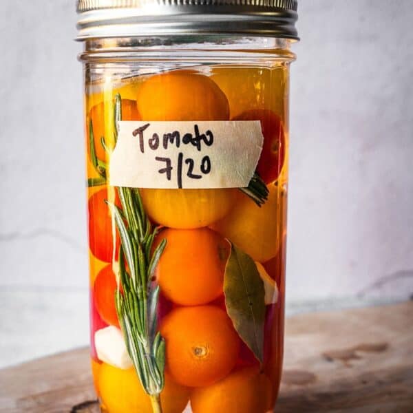 Mason jar with rosemary, garlic, bay and cherry tomatoes.