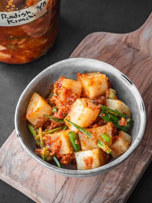 A bowl with Korean Radish Kimchi on a wooden board.