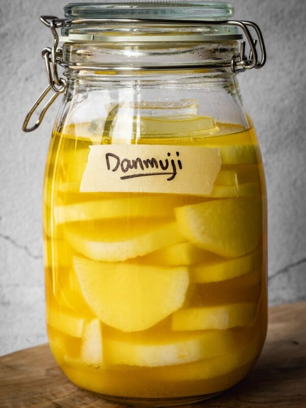 A jar with sliced daikon radish in a pickling solution, with a Danmuji label.