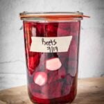 A packed mason jar with sliced beets, garlic and brine.