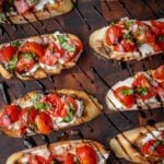 Recipe step showing the finished goat cheese bruschetta with sliced cherry tomatoes, shallots and basil and finished with a balsamic drizzle.