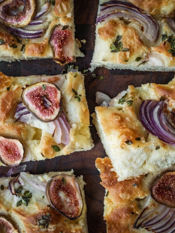 Fig, onion and cheese focaccia slices on a board.