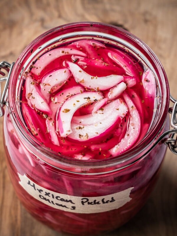 An opened jar of pickled Mexican onions with a label on a wooden board.