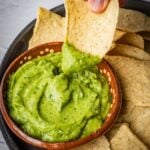 Dipping a nacho chip into the avocado salsa.