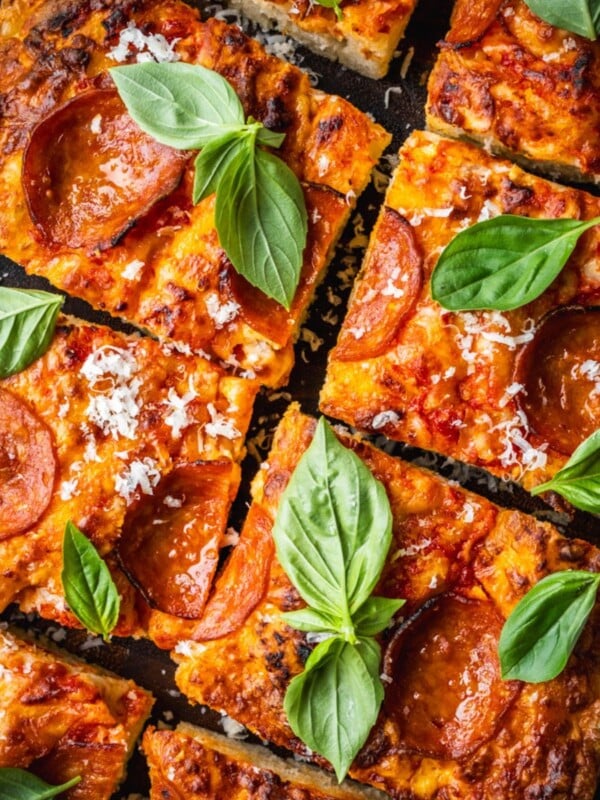 Focaccia pizza sliced with pepperoni and fresh basil.