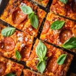 Focaccia pizza sliced with pepperoni and fresh basil.