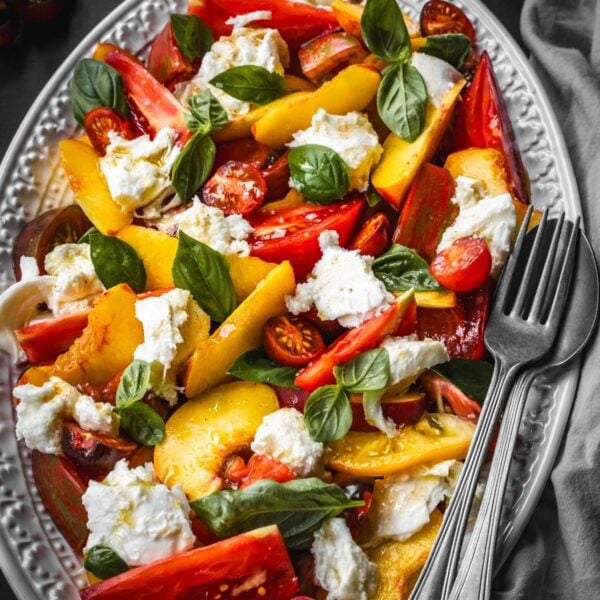 Peach caprese salad with sliced peaches, heirloom tomatoes, basil and mozzarella.