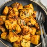 Bowl of garlic and rosemary roasted potatoes with parsley garnish.