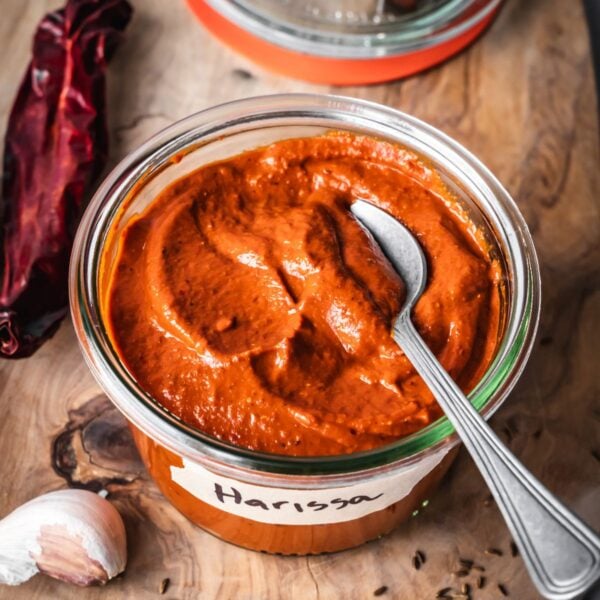 An open jar of harissa paste on a board.