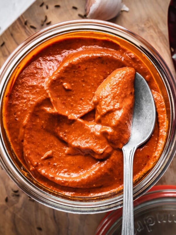 An open jar of harissa paste on a board.