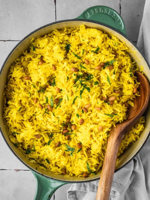 Mediterranean yellow rice in a pot garnished with pine nuts and fresh parsley.