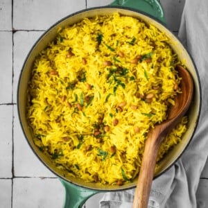 Mediterranean yellow rice in a pot garnished with pine nuts and fresh parsley.