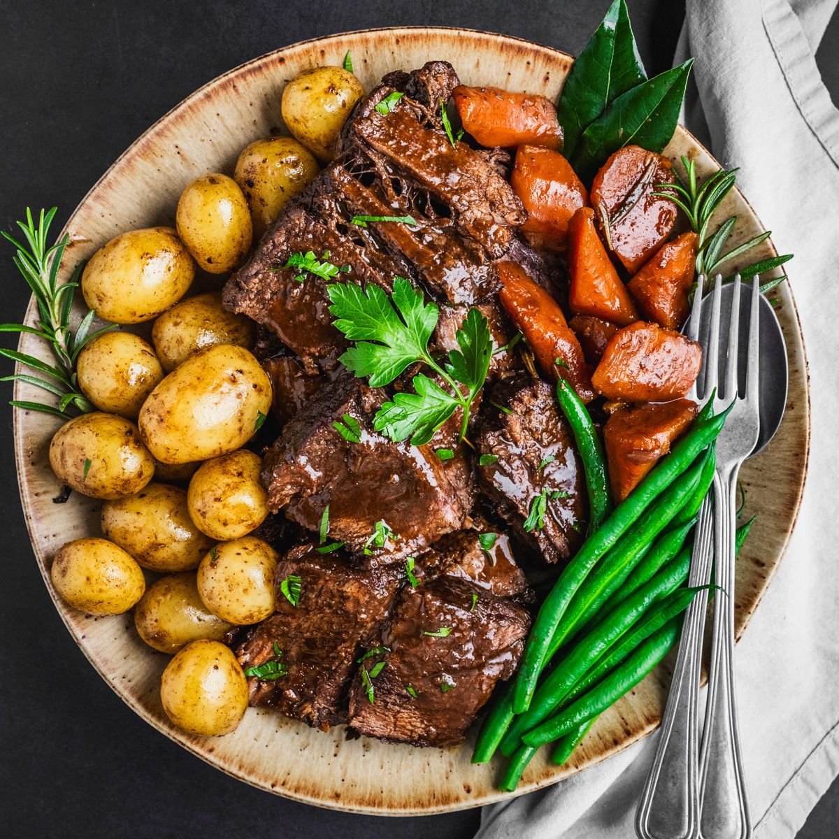 Platter with braised beef, potatoes and carrots.