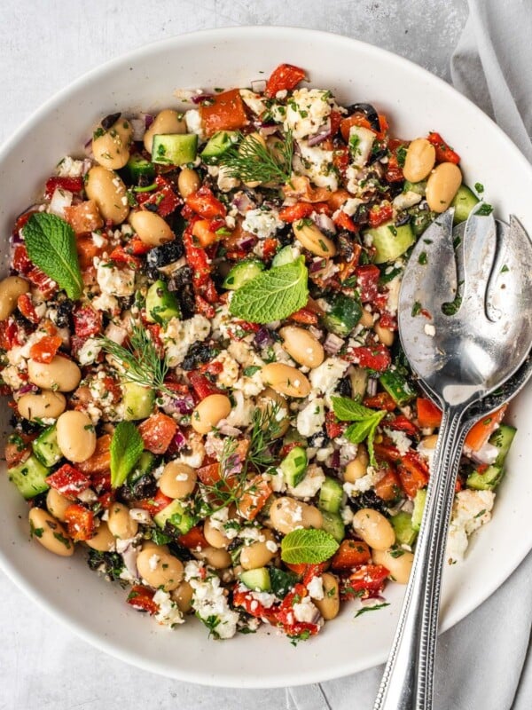 Greek butter bean salad garnished with fresh mint leaves and fresh dill fronds in a large serving bowl.