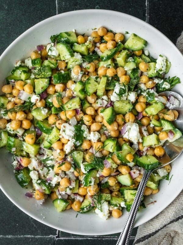 Cucumber chickpea and feta chopped salad in a bowl garnished with dill.