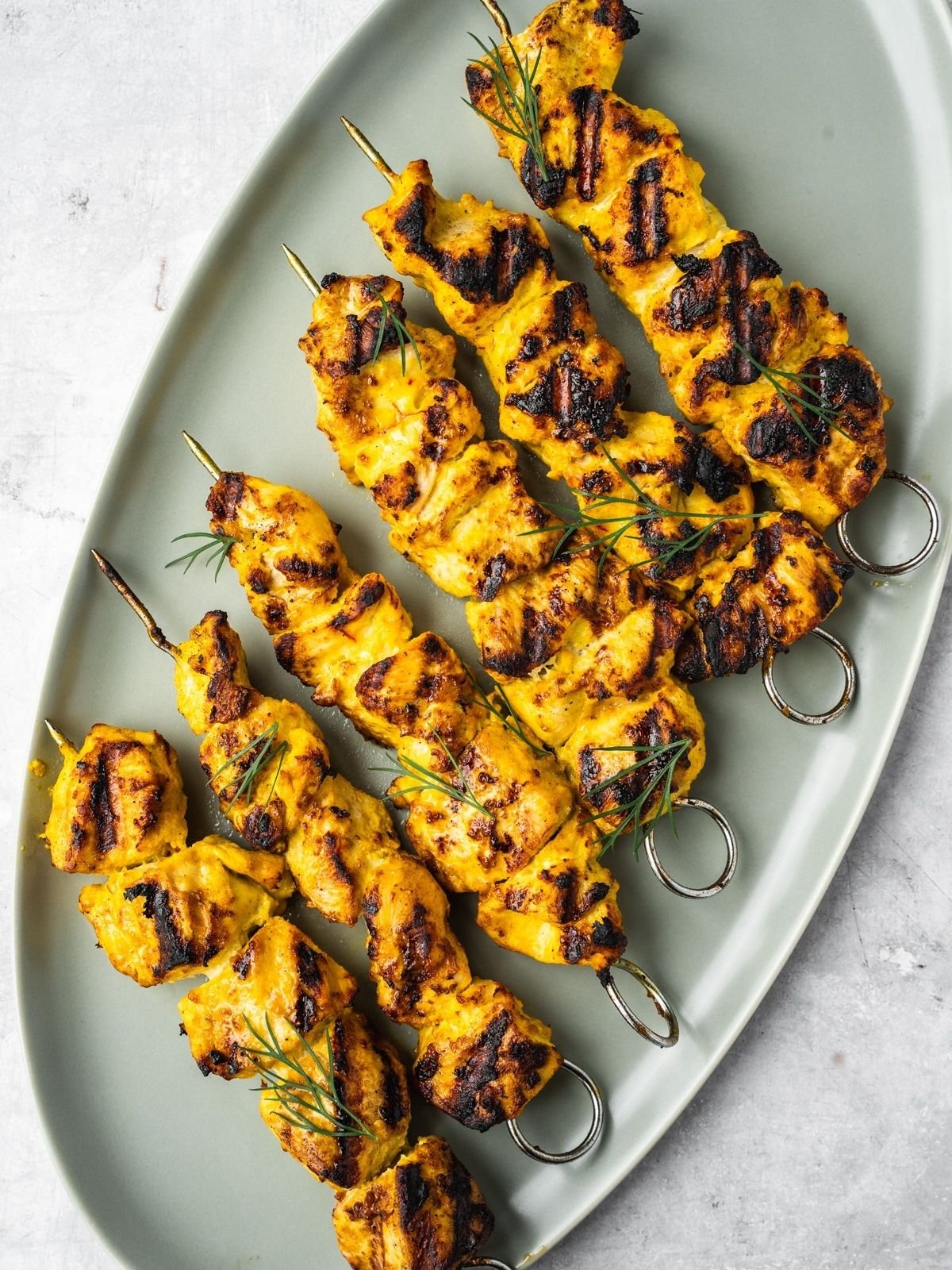 Grilled Joojeh Kabob chicken skewers with a golden char on an oval platter.