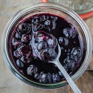 Blueberry Maple Compote in a jar with a spoon.