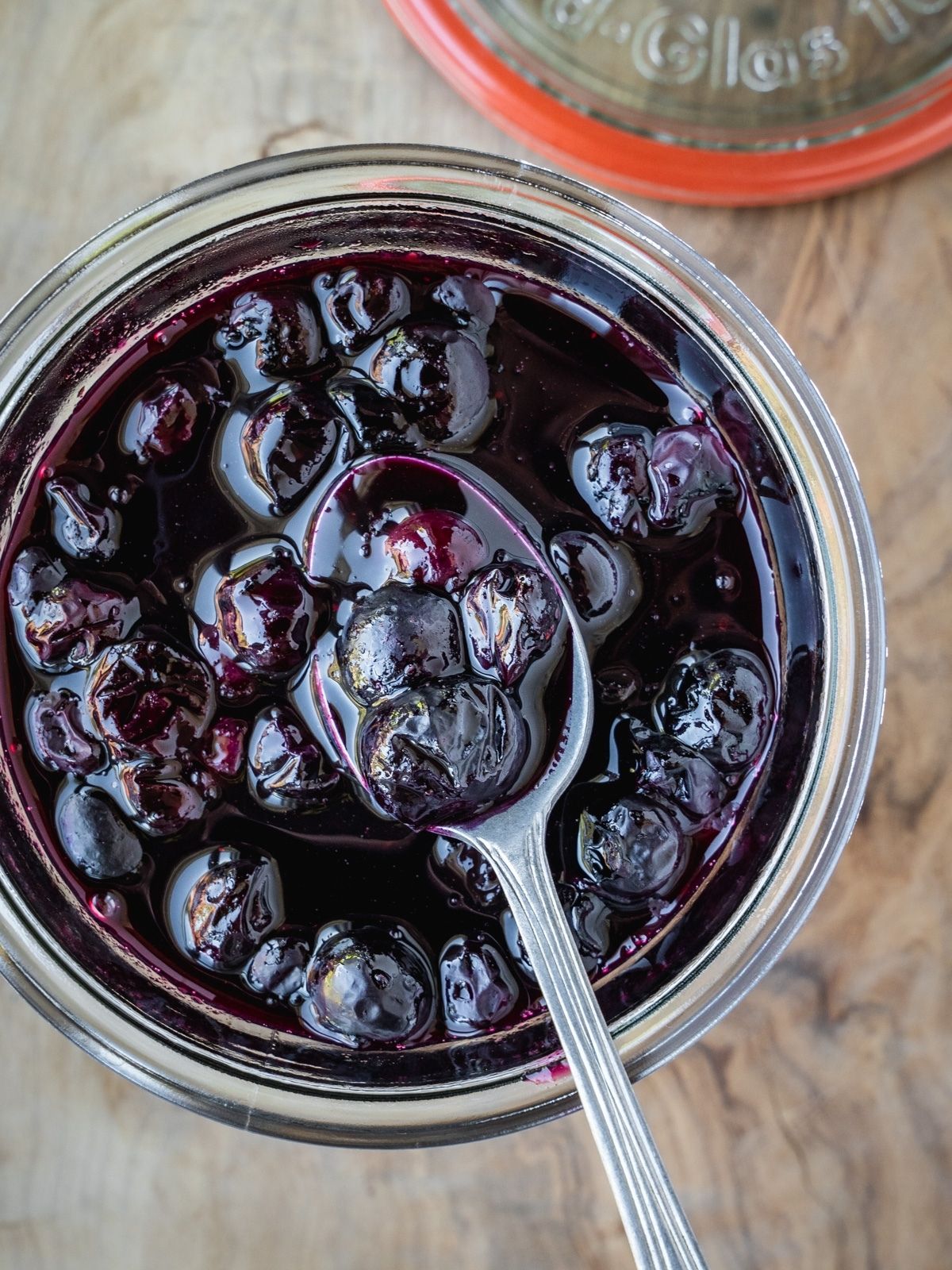 Blueberry Maple Compote in a jar with a spoon.