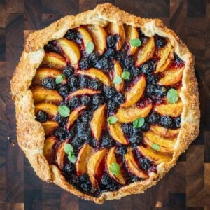 Blueberry Peach Galette garnished with mint on a wooden board.