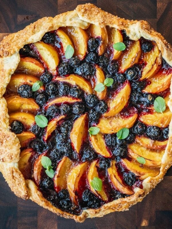 Blueberry Peach Galette garnished with mint on a wooden board.
