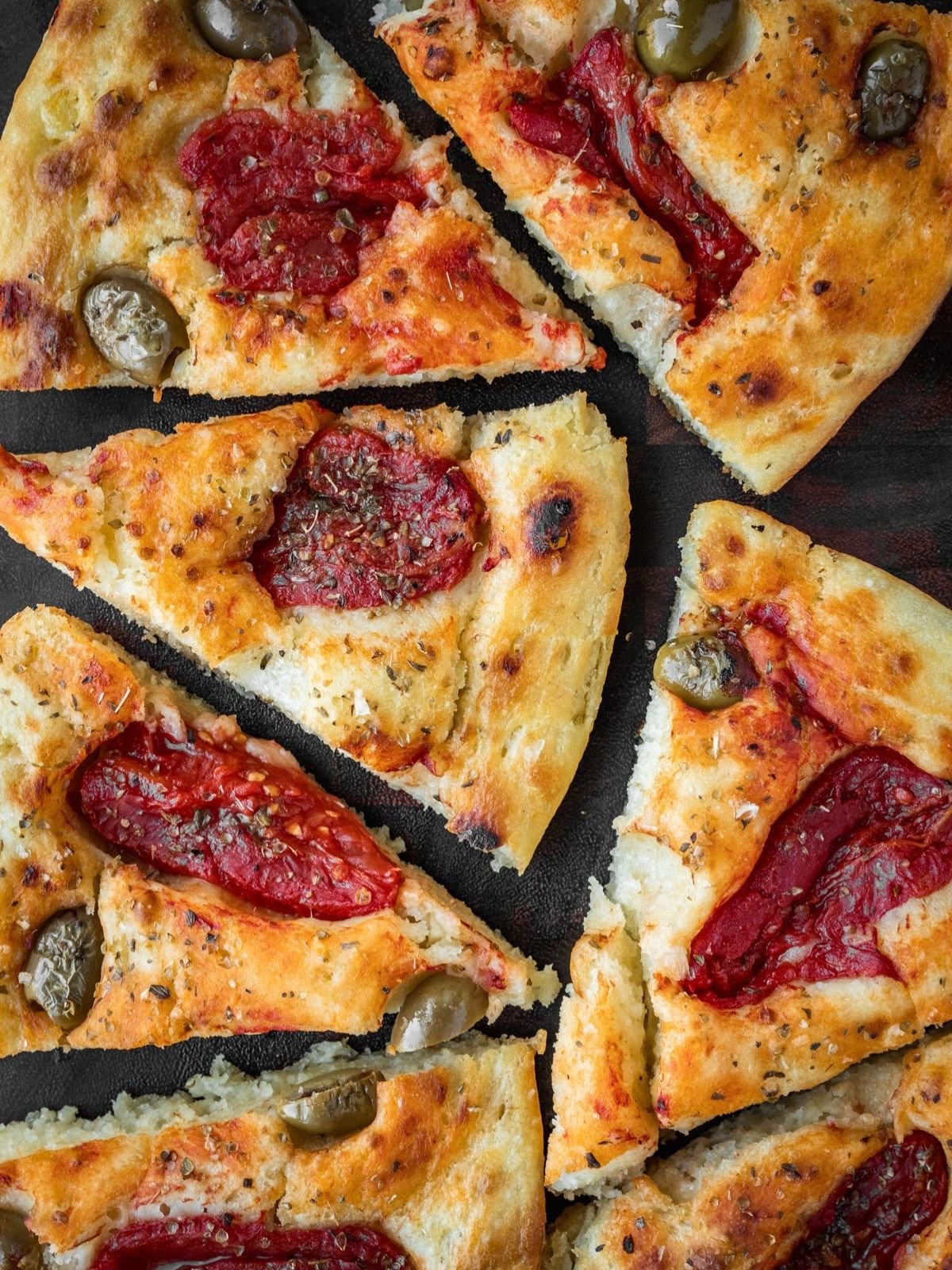 Focaccia Barese slices on a wooden board.