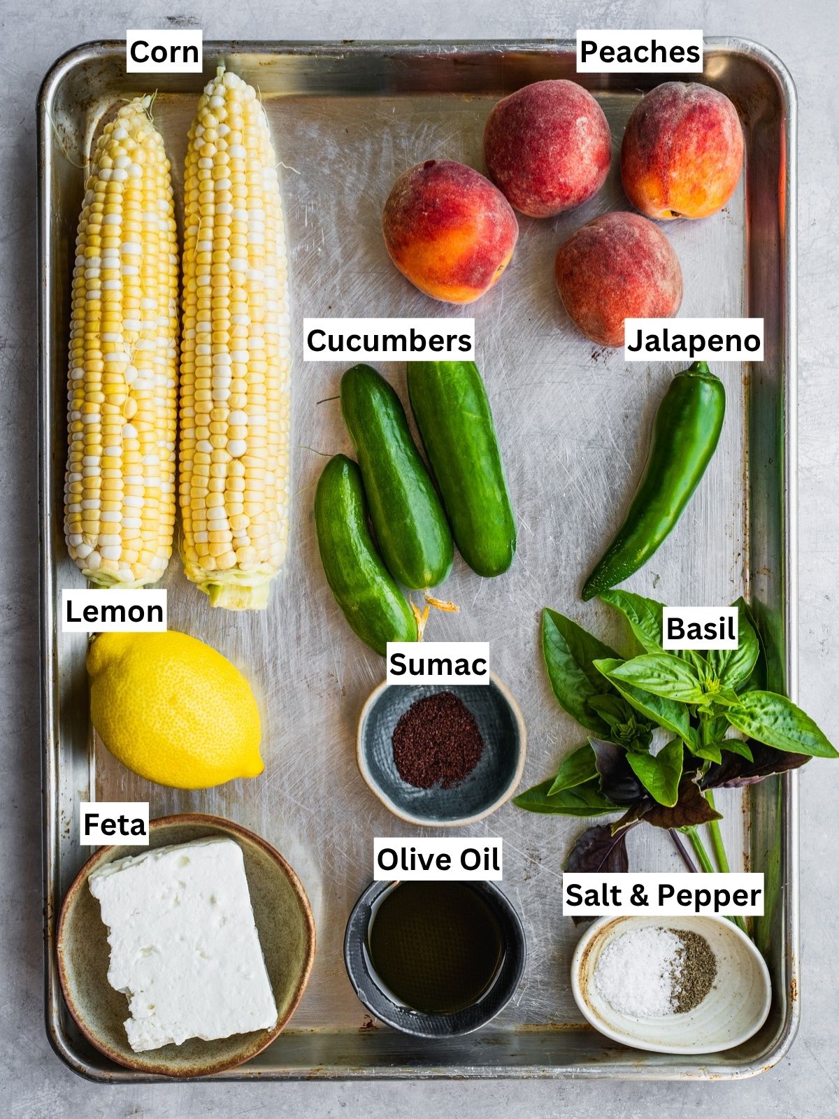 Grilled corn and peach summer salad recipe ingredients with individual labels on a metal tray.