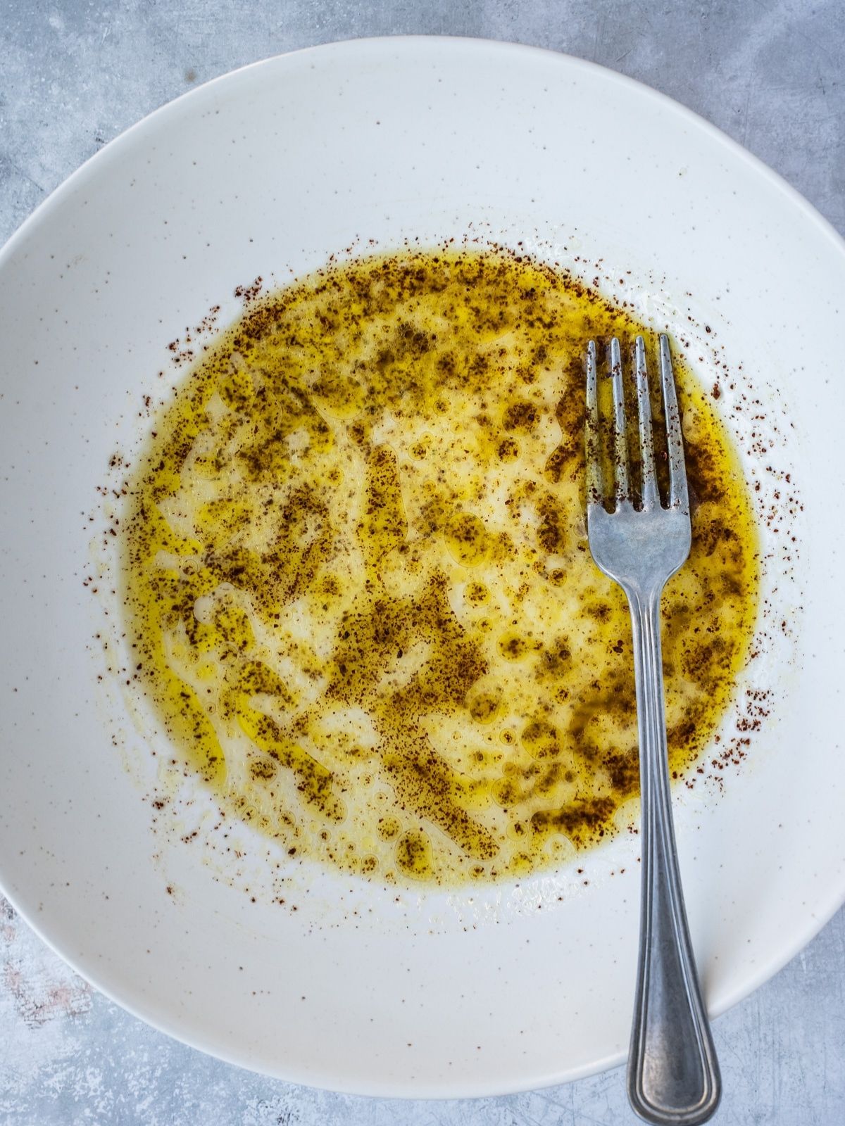Large salad bowl with lemon juice, olive oil, salt, pepper and sumac.
