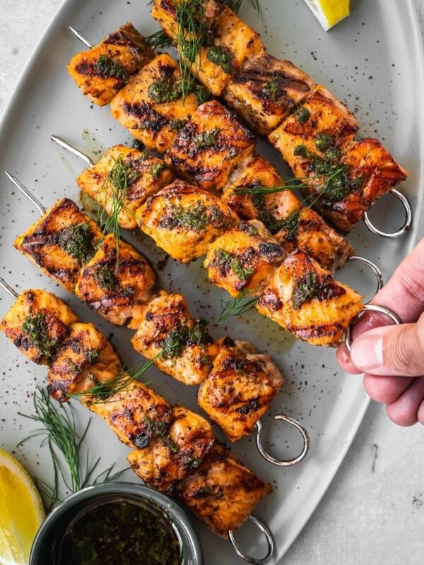 Grilled Mediterranean Salmon Kabobs on a platter garnished with dill and a side of lemon wedges.
