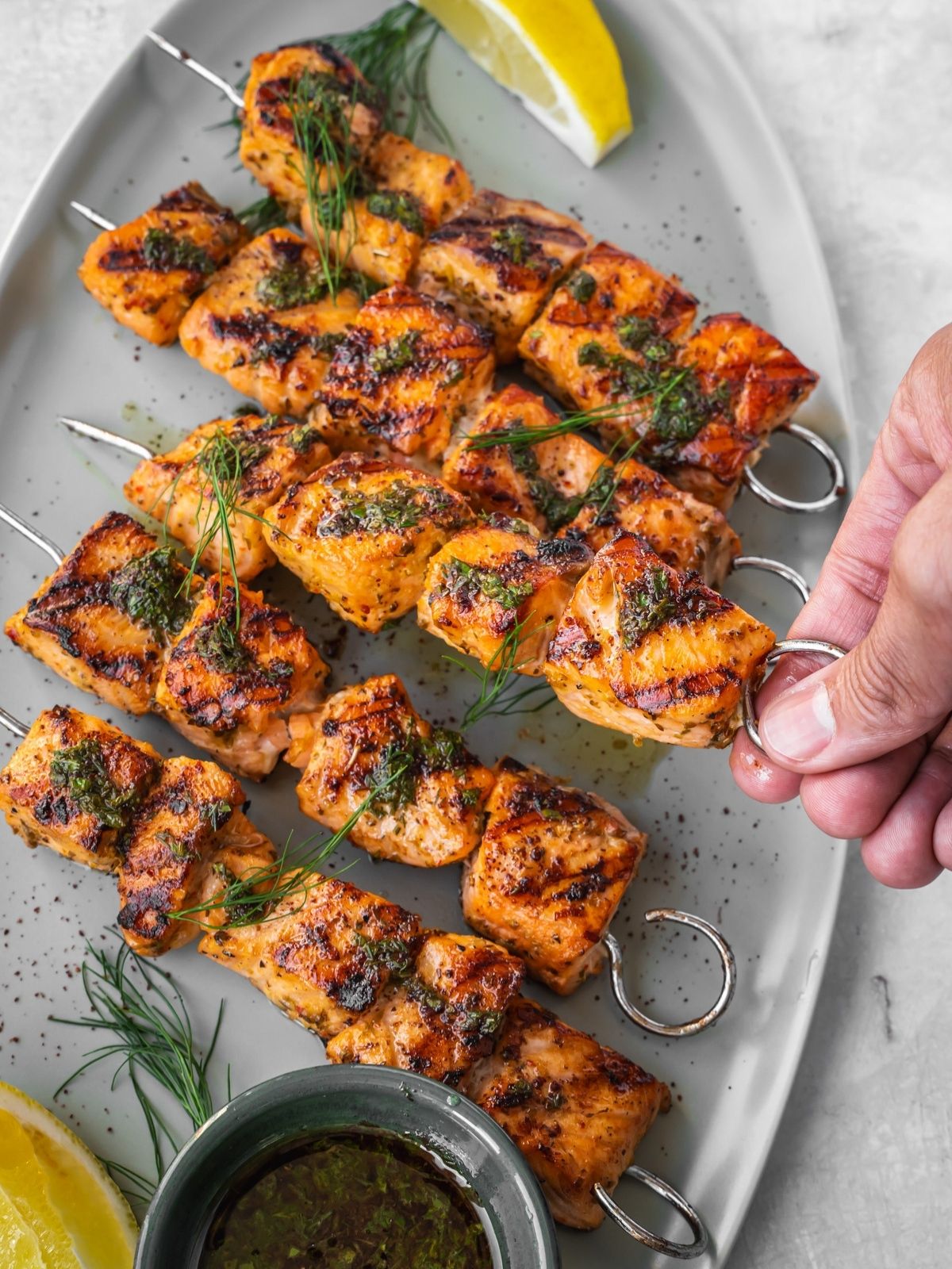 Grilled Mediterranean Salmon Kabobs on a platter garnished with dill and a side of lemon wedges.