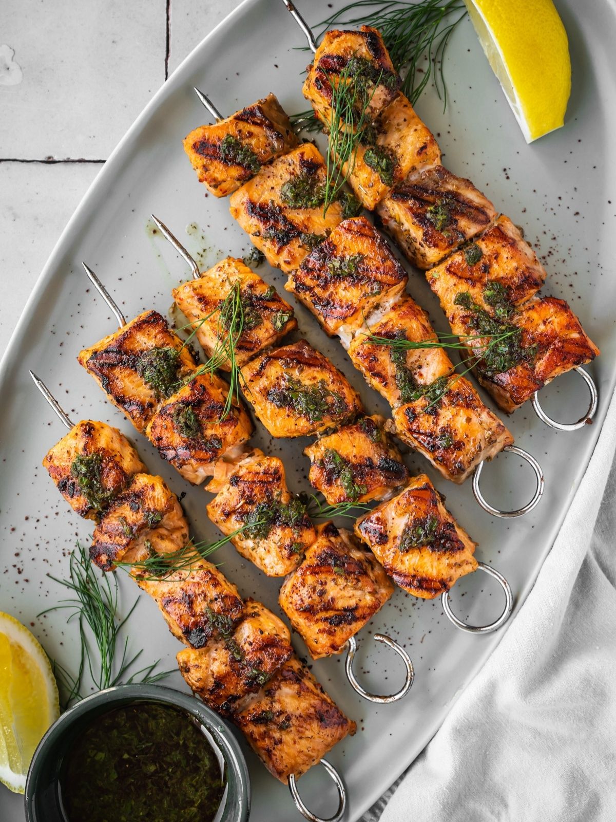Grilled Mediterranean Salmon Kabobs on a platter garnished with dill and a side of lemon wedges.