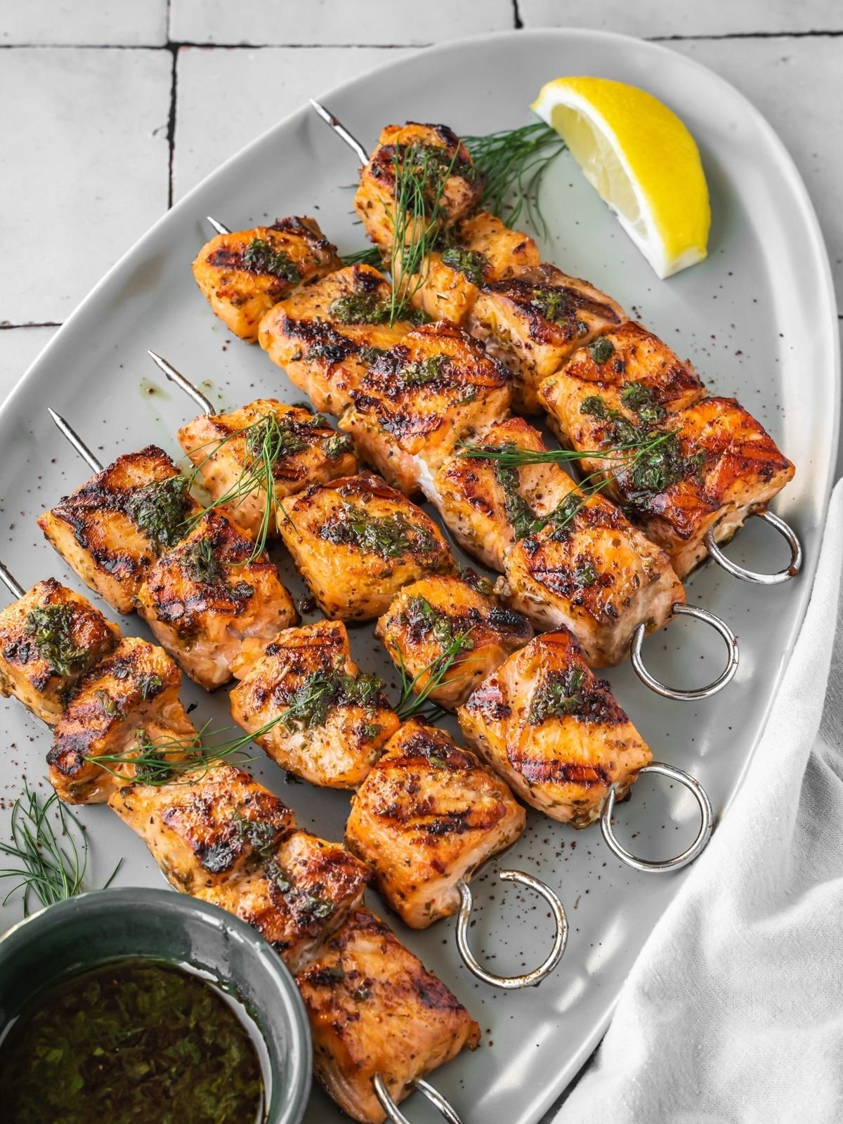 Grilled Mediterranean Salmon Kabobs on a platter garnished with dill and a side of lemon wedges.