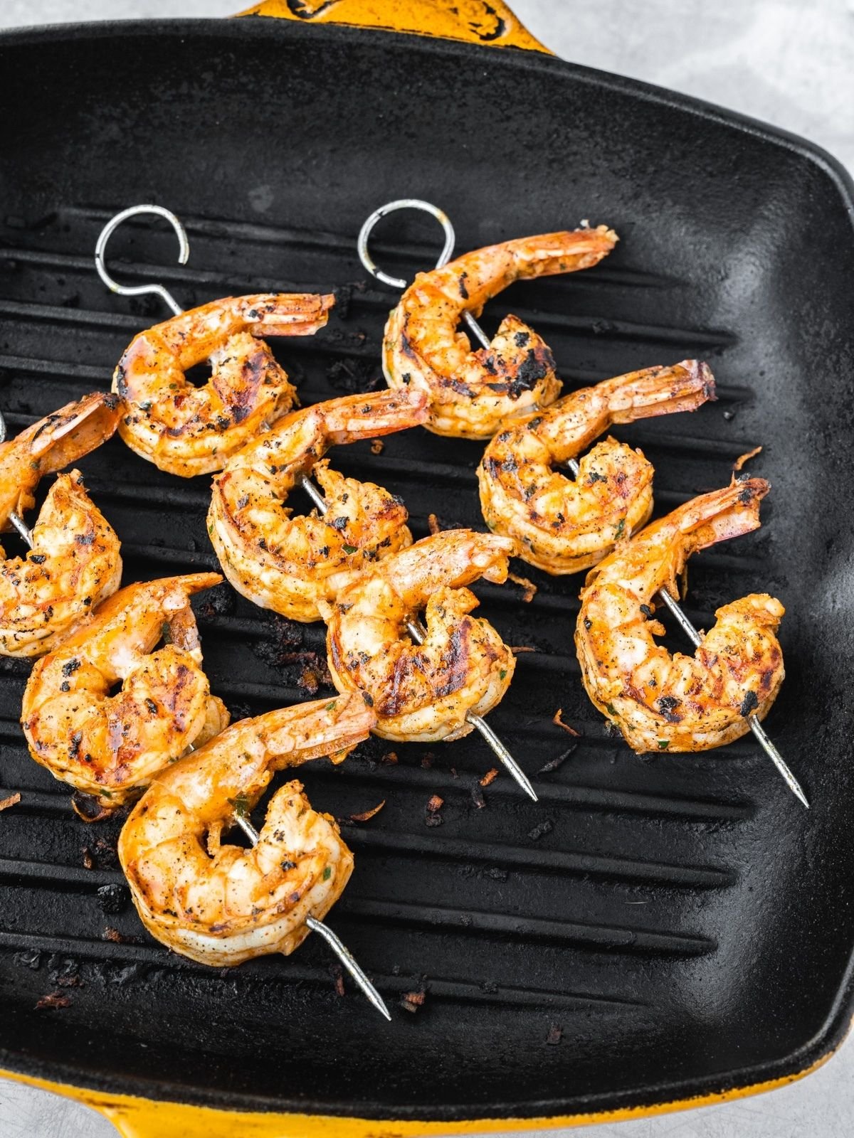 Shrimp skewers grilling on a grill pan.