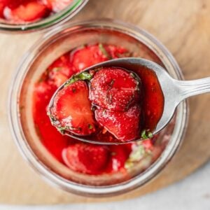 A spoonful of macerated strawberries with sliced basil.