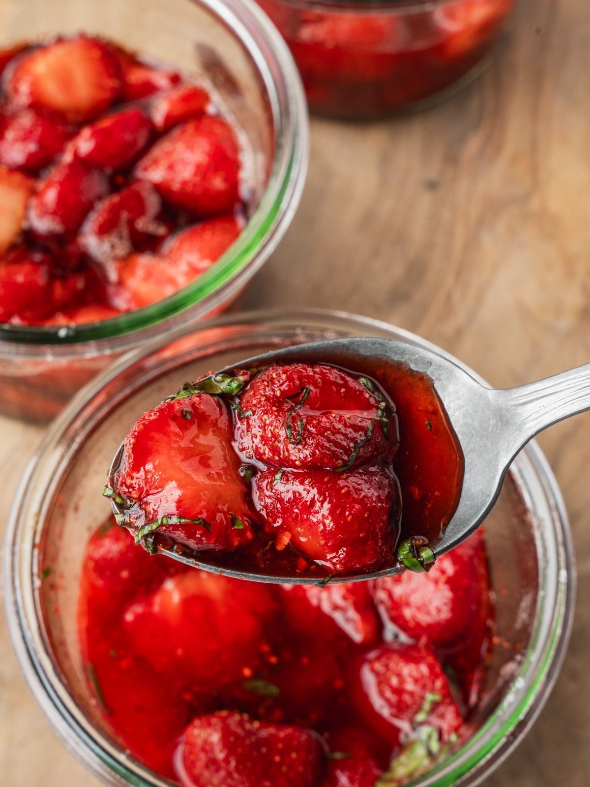 A spoonful of macerated strawberries with sliced basil.