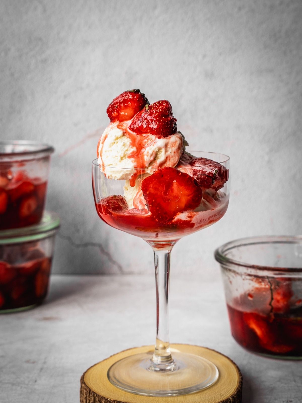 A vanilla ice cream bowl with macerated strawberries and syrup.