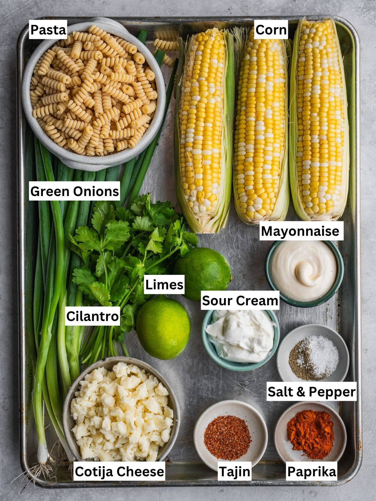 Mexican-inspired elote pasta salad recipe ingredients with individual labels laid out in a tray.