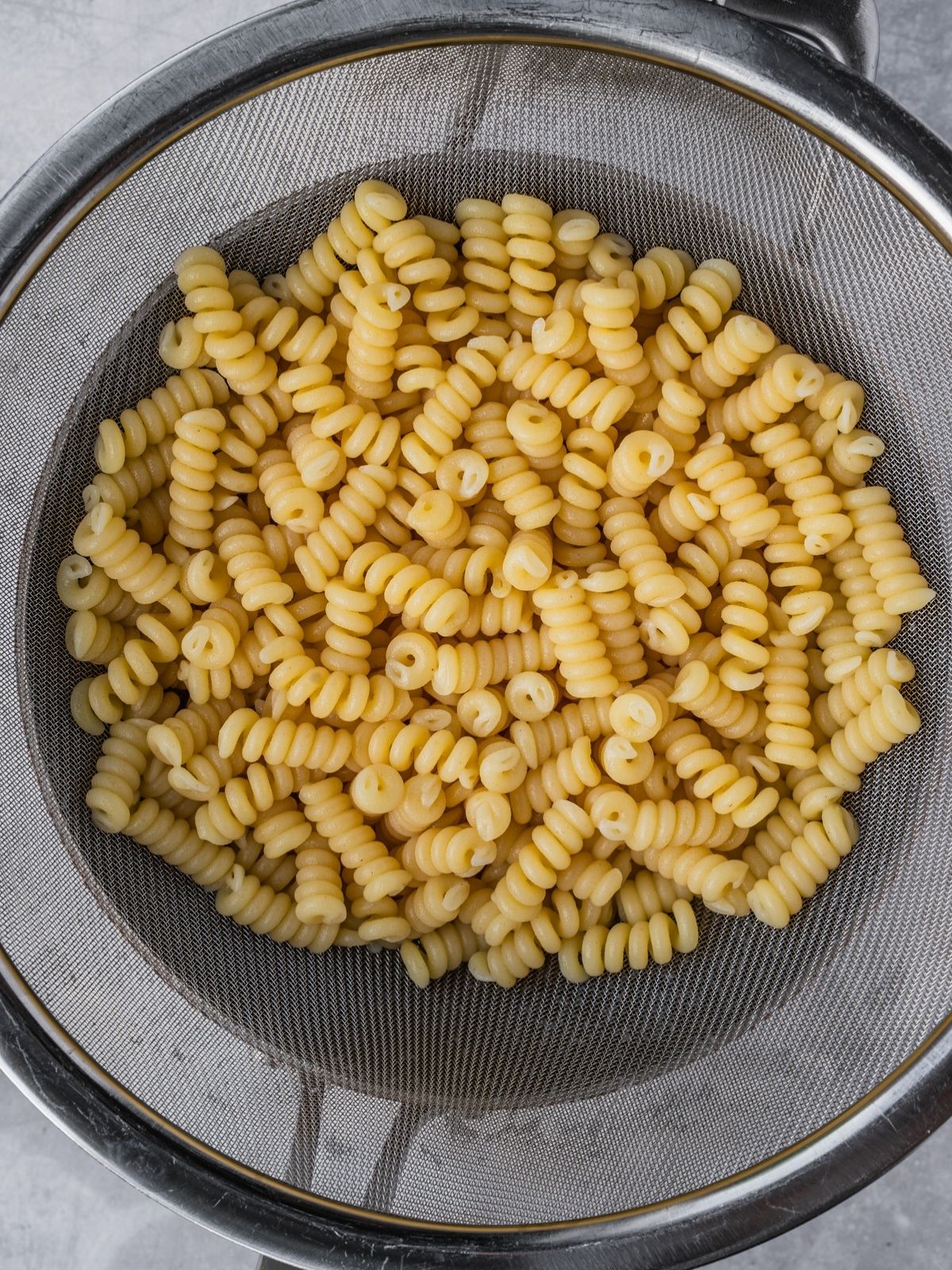 Cooked pasta is draining in a colander.