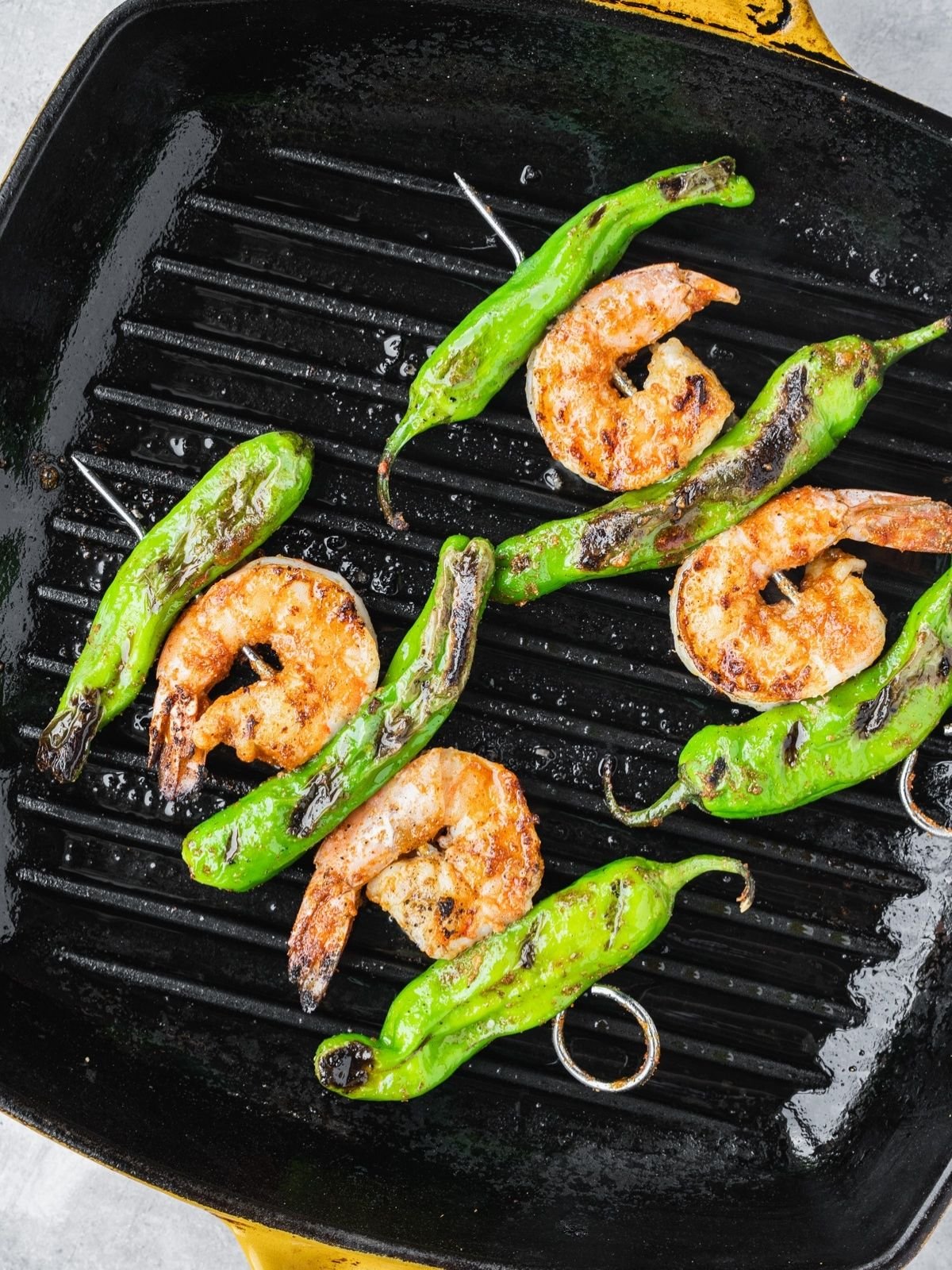 Grill pan with two skewers grilling.