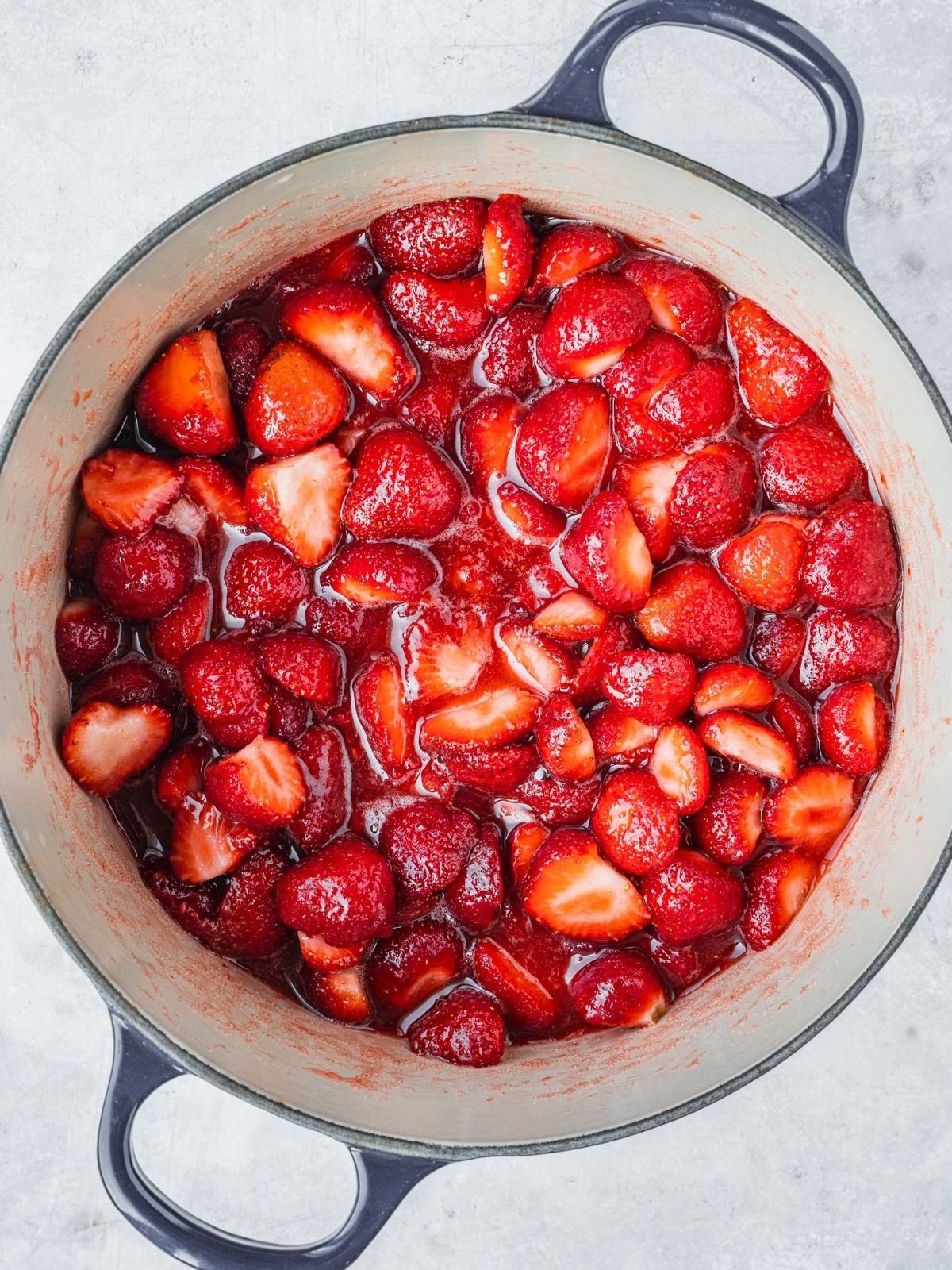 Recipe step showing the strawberries, sugar and lemon starting to cook.