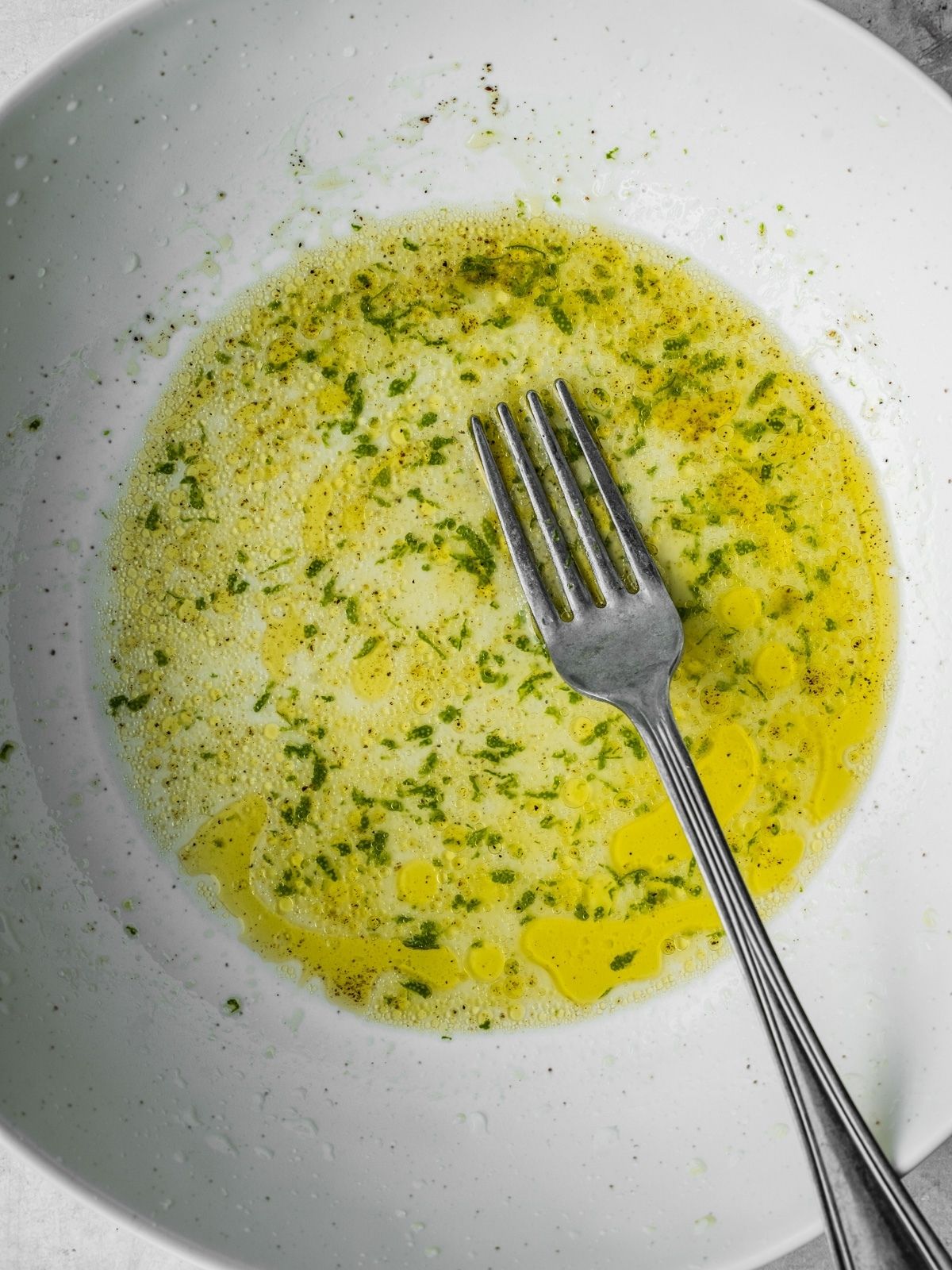 Olive oil, lime juice, lime zest, salt and pepper in a serving bowl.