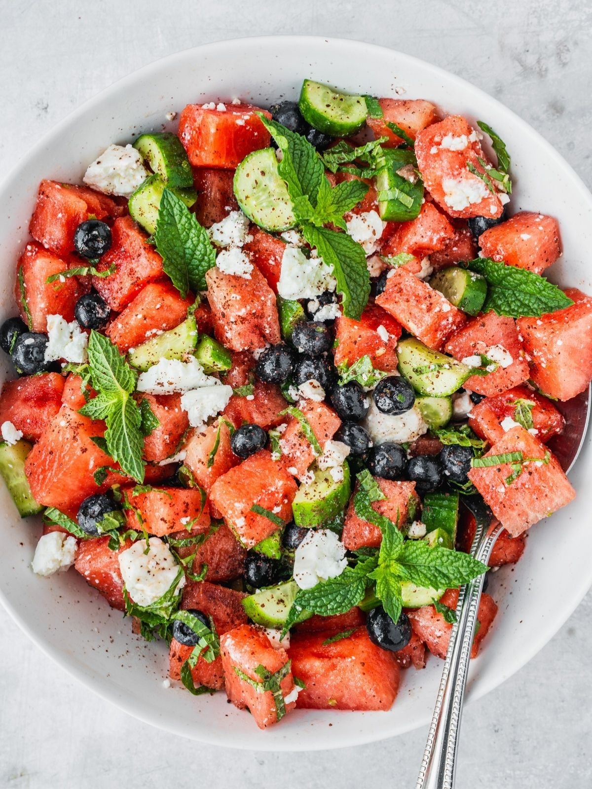Watermelon blueberry feta salad with fresh mint and cucumber in a serving bowl.