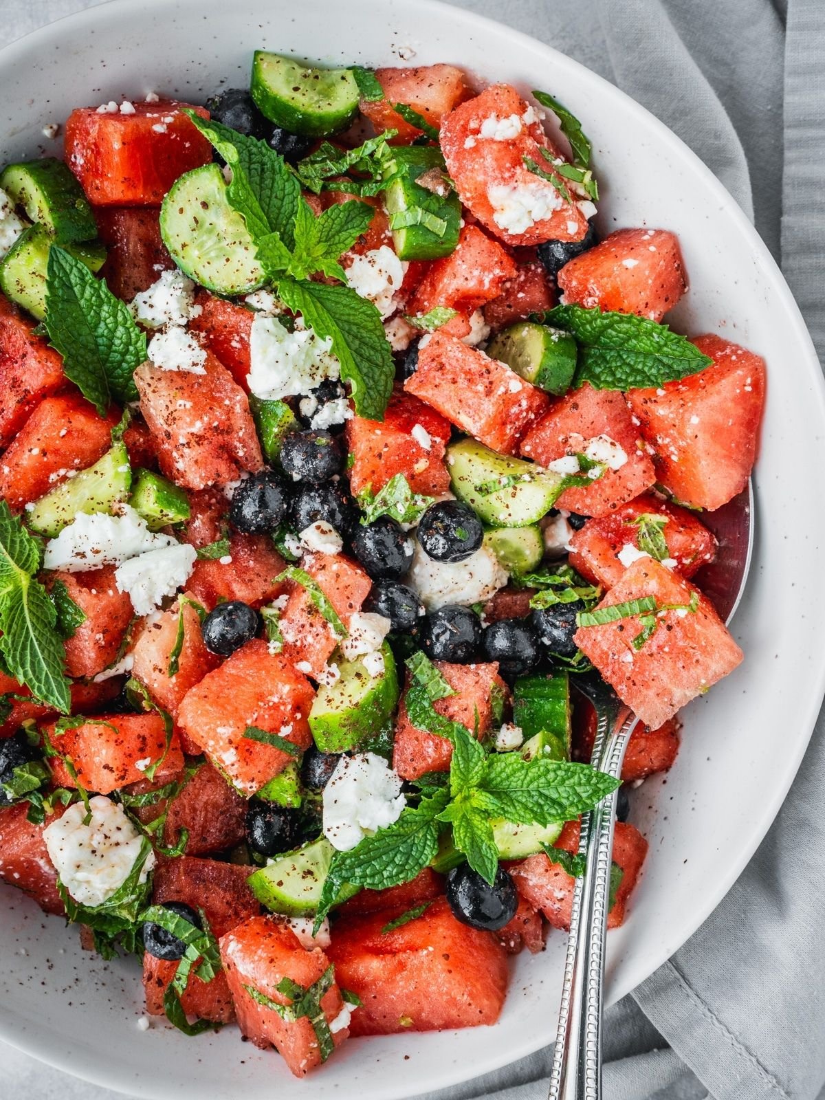 Watermelon blueberry feta salad with fresh mint and cucumber in a serving bowl.