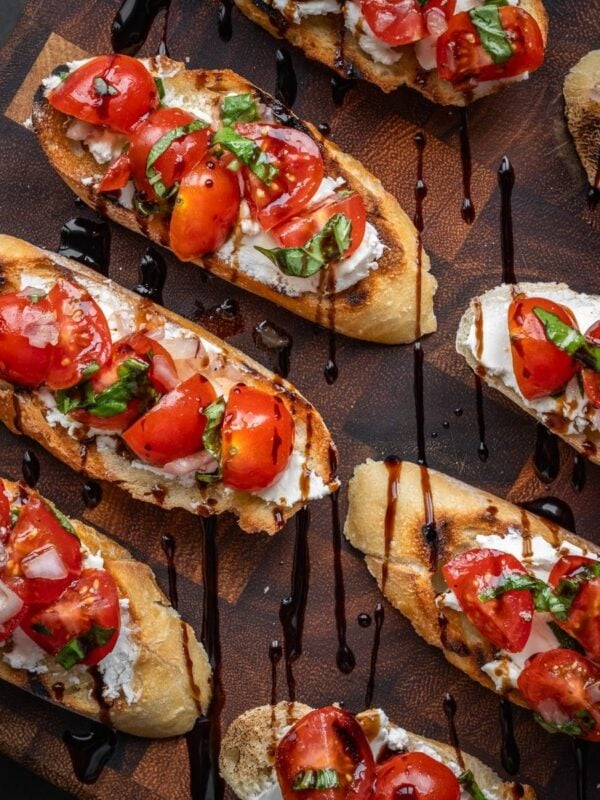 Tomato and goat cheese bruschetta on a board.