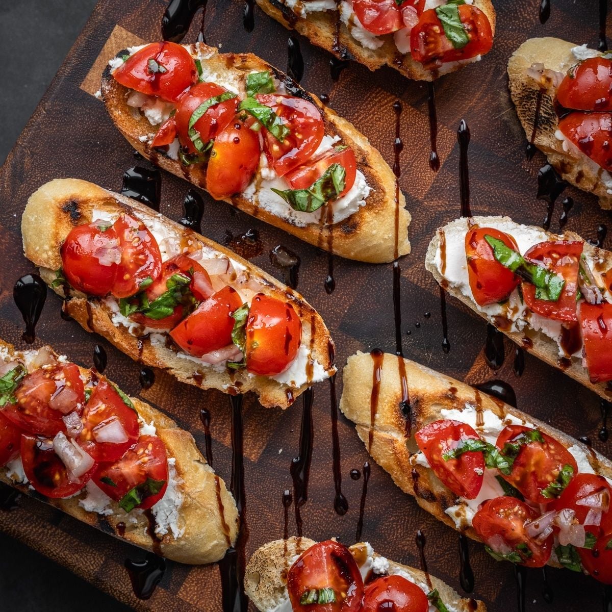 Tomato and goat cheese bruschetta on a board.