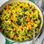 Middle Eastern Vegetable Rice Pilaf with peas, carrots and black beans, garnished with fresh parsley in a pot.