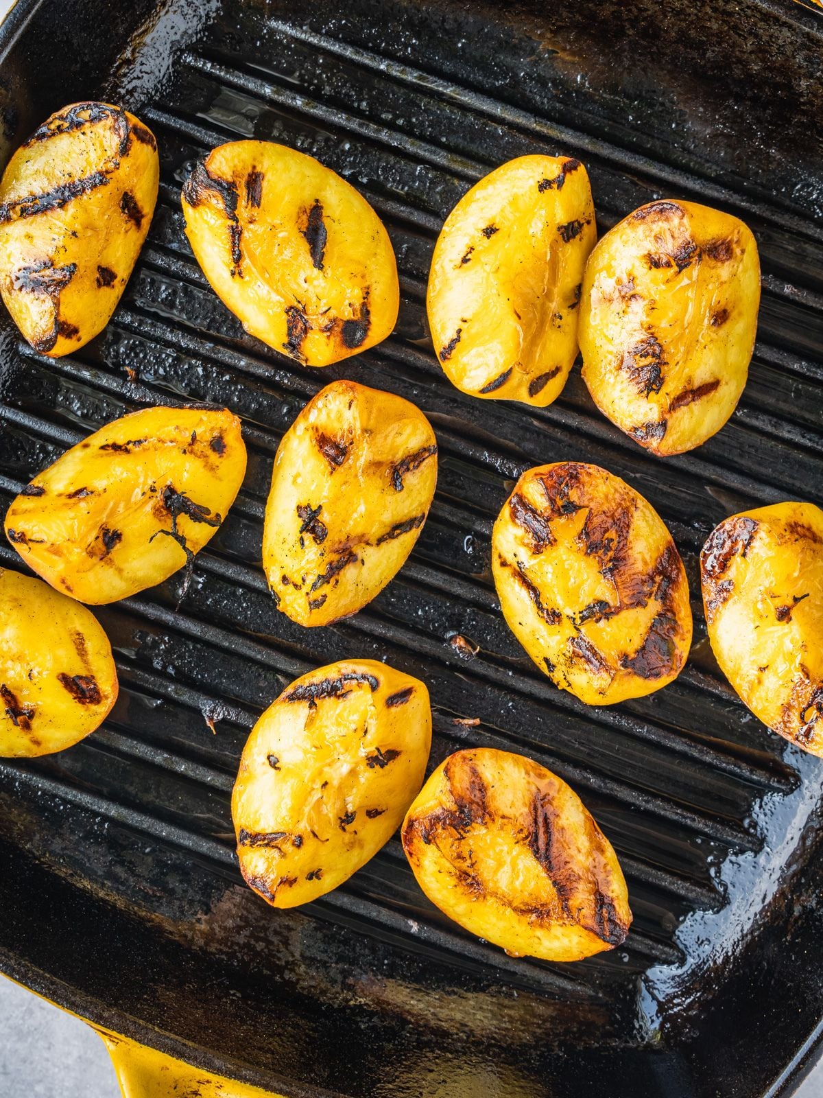 Peach wedges grilling on a grill pan.