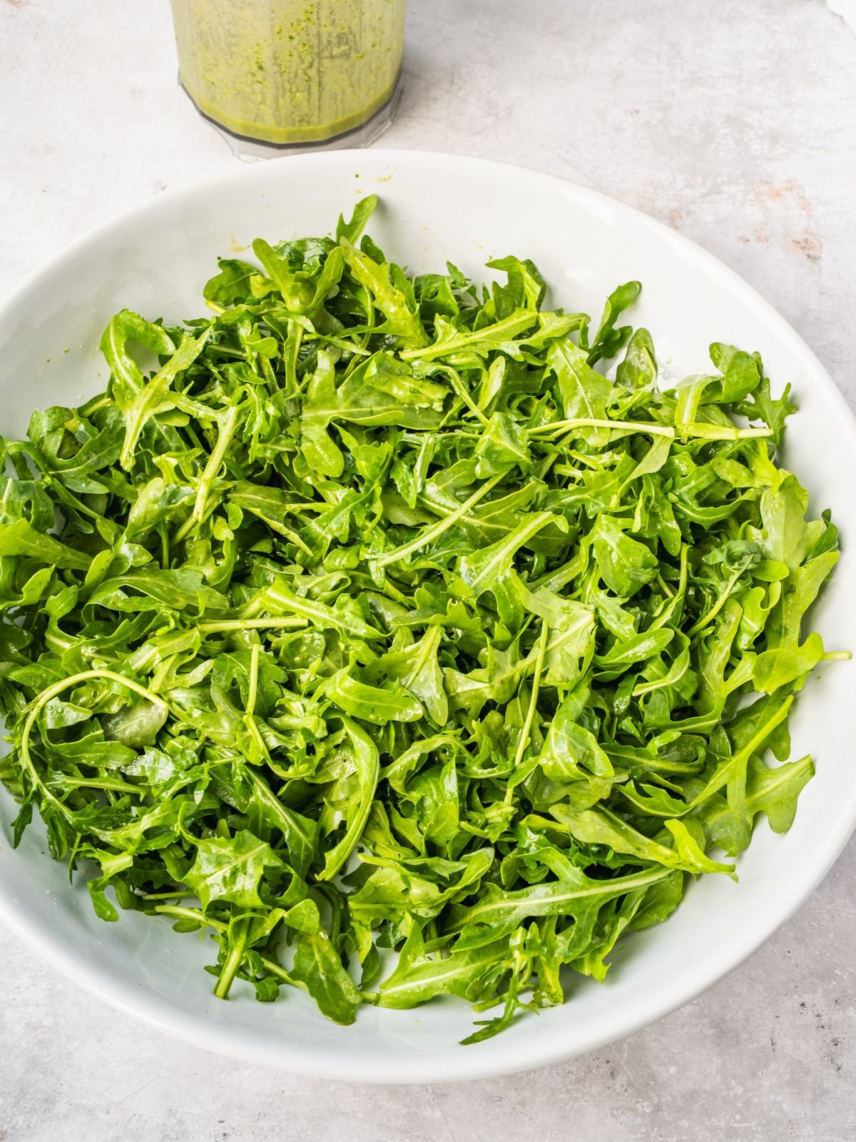Large serving platter with arugula tossed in dressing.