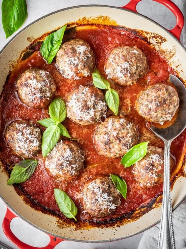 Italian Meatballs simmering in marinara, garnished with fresh basil and Parmesan.